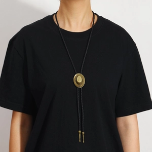Detail of vintage bronze cowboy hat pendant on black braided bolo tie for men