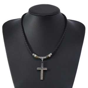 Macro detail of alloy cross pendant with Spanish scripture on braided leather cord