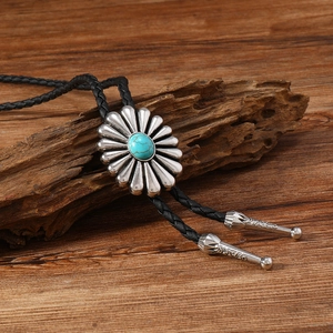 Détail de la cravate bolo avec boucle tournesol, turquoise et embouts en métal gravé