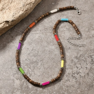 Détail du collier bohème en perles de coco avec pierres colorées sur fond de roche