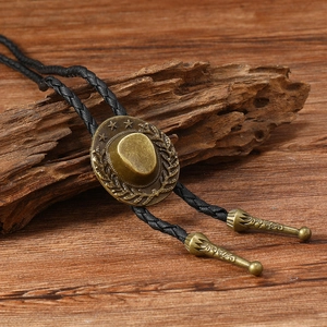 Macro view of bronze cowboy hat bolo tie pendant with braided black leather rope texture