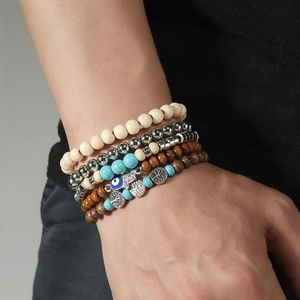Detail of beaded bracelet set featuring turquoise, wood beads, tree of life, and evil eye charms