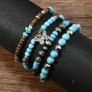 Détail d'un ensemble de bracelets bohèmes avec perles turquoise et pendentif papillon argenté