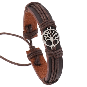 Close-up of leather braided bracelet featuring a silver Tree of Life charm and cord detail