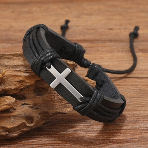 Detail macro view of men's punk leather woven bracelet with silver cross on wood
