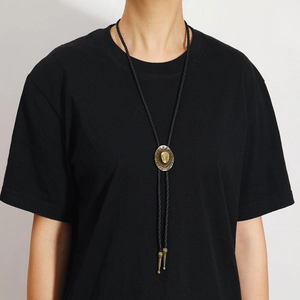 Vintage gold cowboy hat bolo tie pendant on black braided cord worn over black shirt