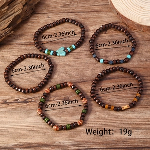 Détail de cinq bracelets bohèmes en perles de bois avec breloques papillon turquoise