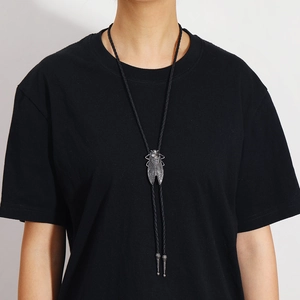 Detailed close-up of a vintage silver cicada bolo tie on a black woven leather cord