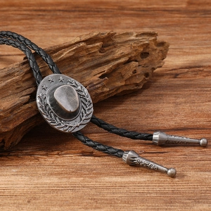 Detail of vintage silver bolo tie featuring embossed cowboy hat on rustic wood background