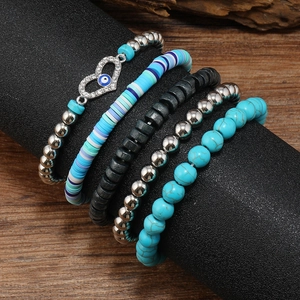 Close-up of bohemian 5-piece stacked bracelets with turquoise beads and evil eye pendant