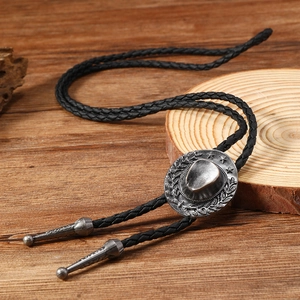 Detailed view of vintage silver bull head bolo tie on rustic wooden display stand