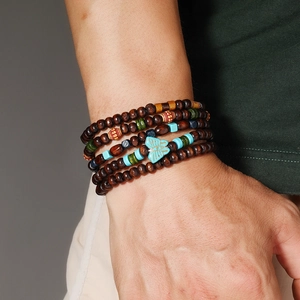 Détail du bracelet multicouche bohème en perles de turquoise et bois avec motif papillon