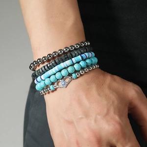 Detail of stacked turquoise beads and heart evil eye charm bracelet on wrist