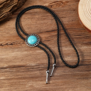 Gros plan sur la cravate bolo turquoise avec gravure argentée sur fond bois foncé