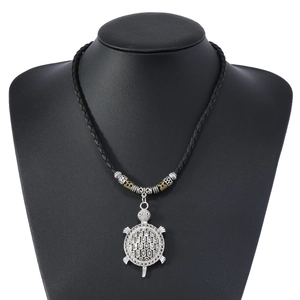 Close-up of silver turtle pendant with honeycomb pattern on a black braided cord necklace