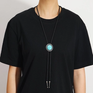 Gros plan sur une cravate bolo vintage avec turquoise et gravure détaillée en métal argent