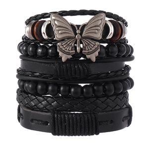 Détail d'un bracelet bohème multicouche avec cuir noir, perles et un grand papillon argenté