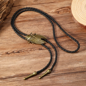 Detailed close-up of retro dragonfly bolo tie with bronze alloy pendant and woven leather cord