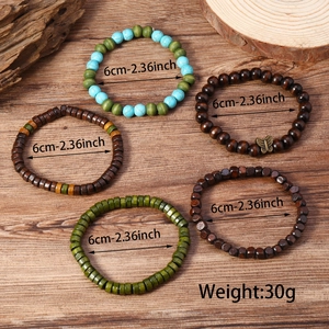 Gros plan de bracelets bohèmes en bois et perles de turquoise avec un papillon en bronze