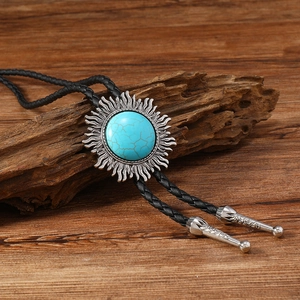 Gros plan de cravate bolo vintage avec turquoise et cuir tressé sur fond bois