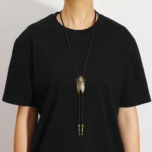 Detail of vintage bronze dragonfly bolo tie pendant with black woven cord on model