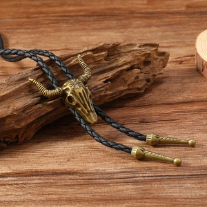 Close-up of vintage bronze bull skull bolo tie with detailed texture on wood
