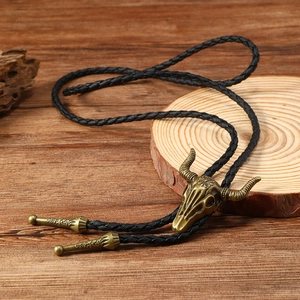 Macro shot of vintage bronze bull skull bolo tie on wood background with braided leather cord