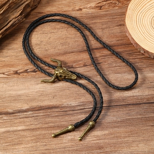 Macro detail of vintage bronze bull skull bolo tie with black braided leather rope