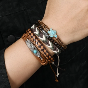 Details der mehrlagigen Boho-Armbänder mit Türkisperlen und Federanhängern am Handgelenk