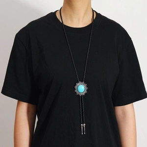 Détail d'une cravate bolo vintage avec turquoise et base en métal soleil sur cordon