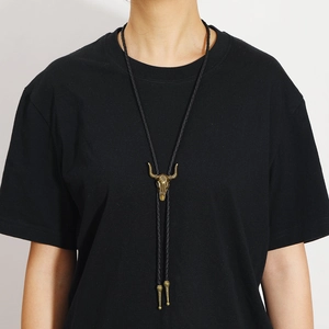 Detail of vintage bronze bull skull bolo tie with black braided leather and sun flower carving