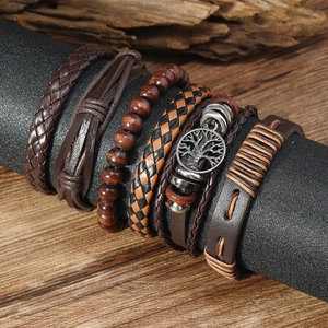 Close-up of stacked leather bracelets for men featuring Tree of Life charm and wooden beads