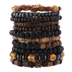 Detail view of multi-layer wood and lava stone beaded bracelets with vintage cross charms