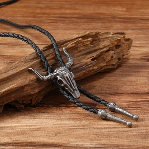 Macro detail of antique silver cow skull bolo tie with floral carving on wood