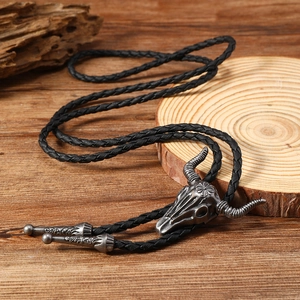 Macro shot of vintage silver bull head bolo tie with woven cord on rustic wood base