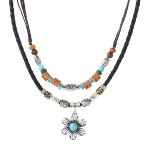 Detail of bohemian layered necklace with turquoise beads and floral metal pendant charm