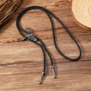 Macro detail of vintage bull skull bolo tie with engraved sun pattern on dark wood background