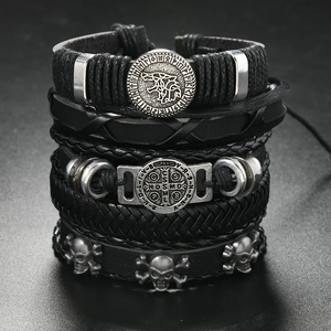 Close-up of punk leather bracelets with skull charms and engraved wolf metal tags