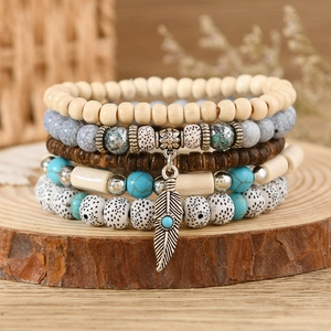 Detail of bohemian layered beaded bracelet featuring turquoise stones and a feather charm