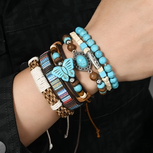 Detail der mehrlagigen Boho-Armbänder mit Türkisperlen und Schmetterlingsanhänger am Handgelenk