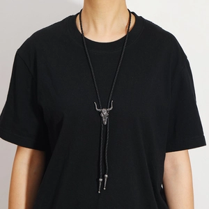 Close-up of vintage bull head pendant with black braided rope and silver bolo tie tips