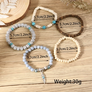 Detail of five-piece Bohemian beaded bracelet set with turquoise and metal feather charm