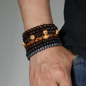 Close-up of stacked men's wood bead bracelets featuring a red cross charm detail