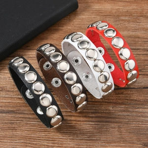 Detail of studded leather bracelets in four colors on a dark wood background