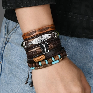 Detail von mehrlagigen Boho-Armbändern mit Türkisperlen, Lederbändern und Feder-Anhängern