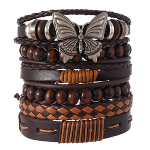 Détail d'un bracelet bohème multicouche avec tresses en cuir, perles de bois et papillon argenté