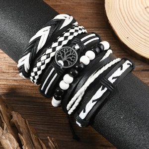 Close-up of multilayer men's leather bracelet set with tree of life charm on wood