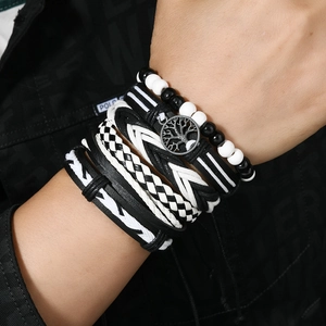 Detail of tree of life charm on men's multi-layer black and white braided leather bracelet