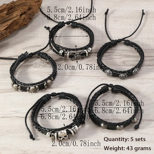 Close-up of five-piece black leather punk bracelets set with skull charms and studs