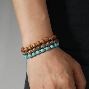 Close-up of stacked beaded bracelets featuring wood, turquoise stones and crystal spacers